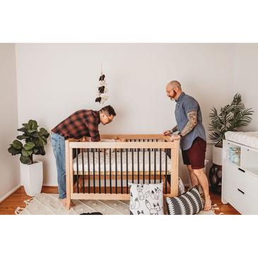 Gay couple in nursery with best crib mattress and changing pad